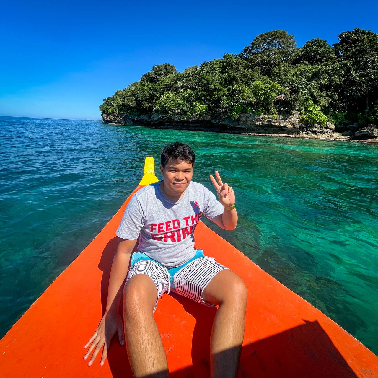 Ingvar riding an orange boat across clear tropical water