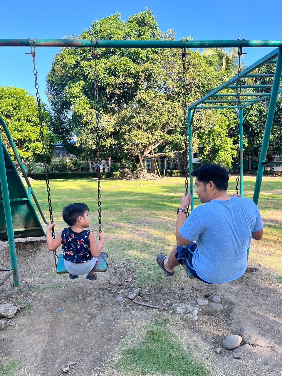 Ingvar sitting on a park swing beside a young child