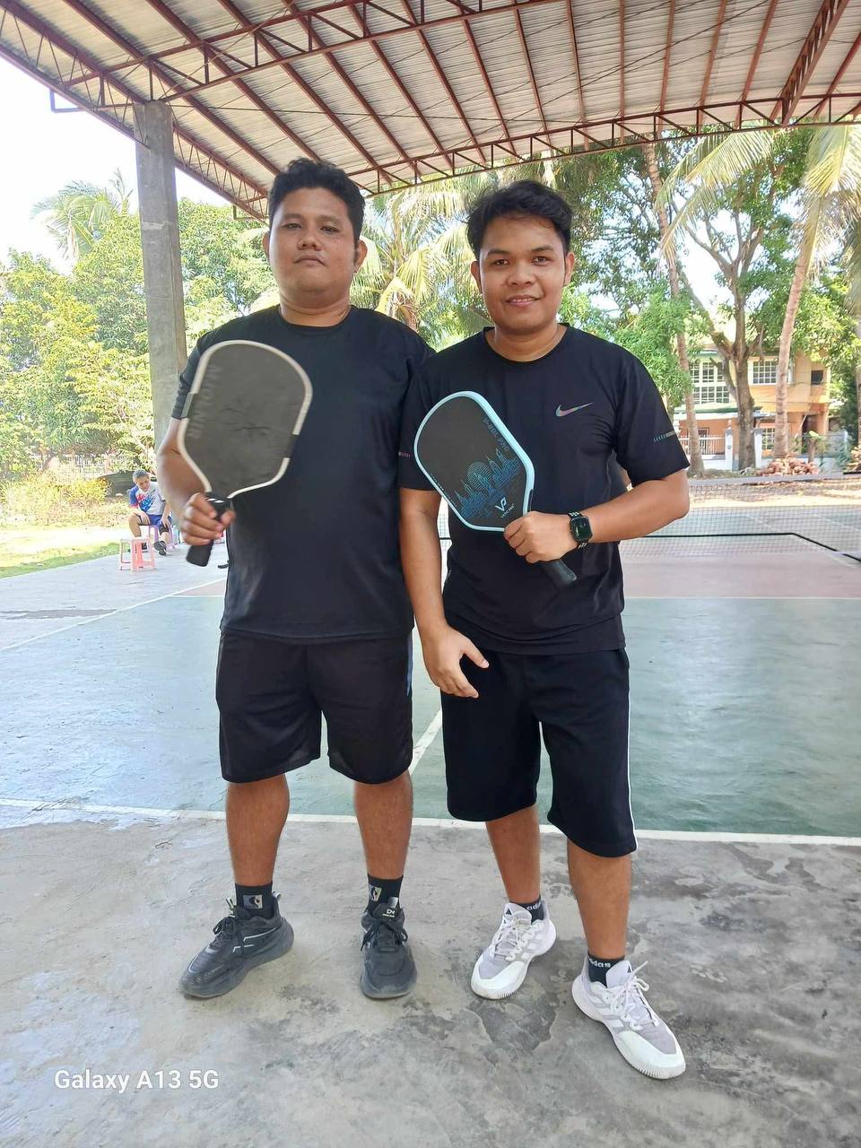 Ingvar and a friend holding pickleball paddles on a court