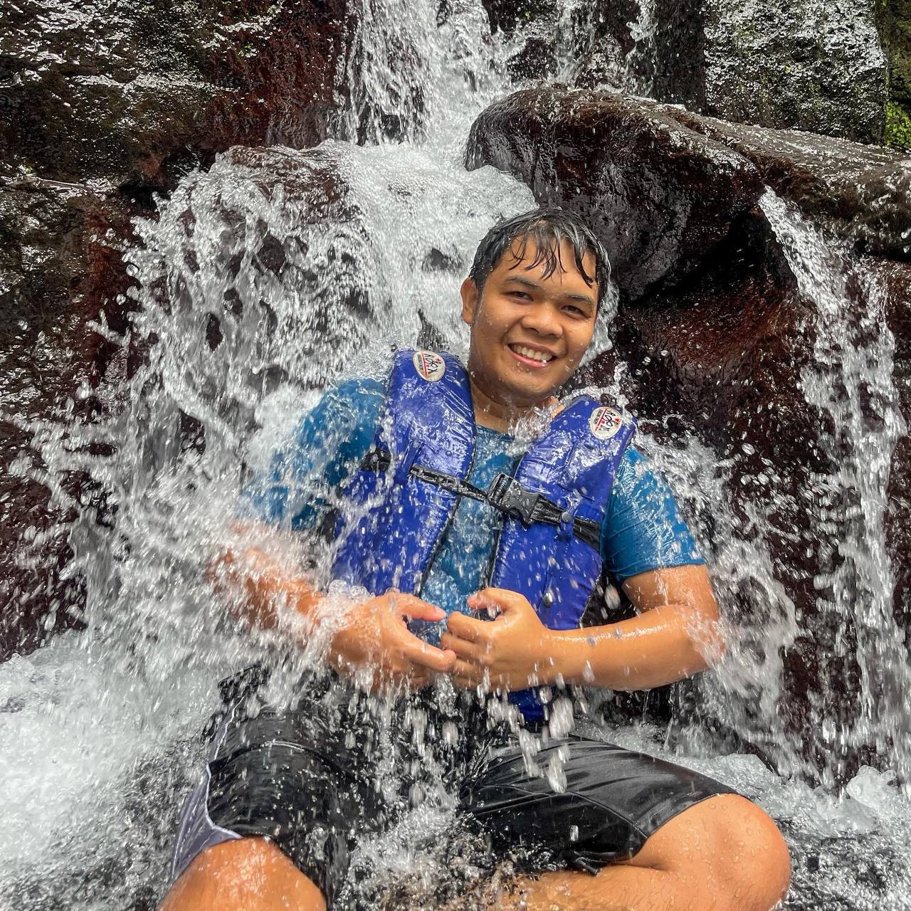 Ingvar Estorco smiling beneath a waterfall